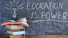Bücher und Tafel mit Zeichnung einer Glühbirne und Slogan Bildung ist Kraft, Lernen, Wissen, Zurück zur Schule Konzept