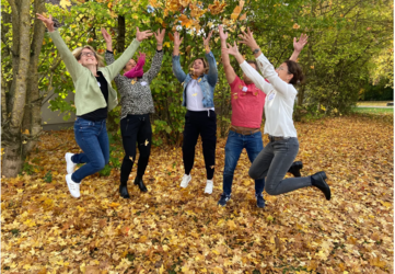 Personen, die mit Herbstlaub in die Luft springen.