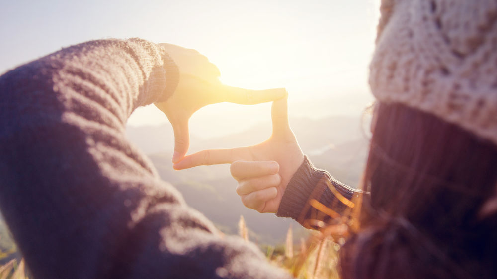 ©iStockphoto.com/oatawa Frau Hände machen Rahmen Geste mit Sonnenaufgang.