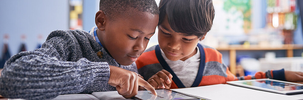 Beschnittene Aufnahme von Grundschulkindern mit einem Tablet im Unterricht