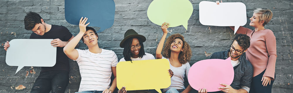 ©iStock\PeopleImages Aufnahme einer vielfältigen Gruppe von Menschen, die draußen Sprechblasen hochhalten.