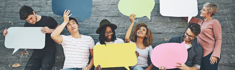 ©iStock\PeopleImages Aufnahme einer vielfältigen Gruppe von Menschen, die draußen Sprechblasen hochhalten.