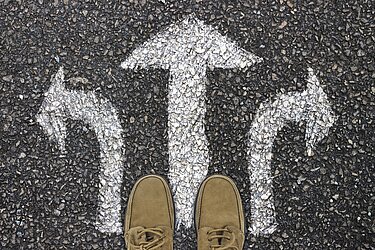 Quelle: Pixaybay; Füße auf einen Straßenbelag mit drei Richtungspfeilen; Bild von Gerd Altmann, 9.11.2019; 