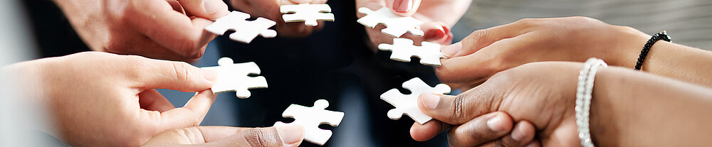 ©iStock\Cecilie Arcurs Hände, die Puzzleteile zusammenschieben.