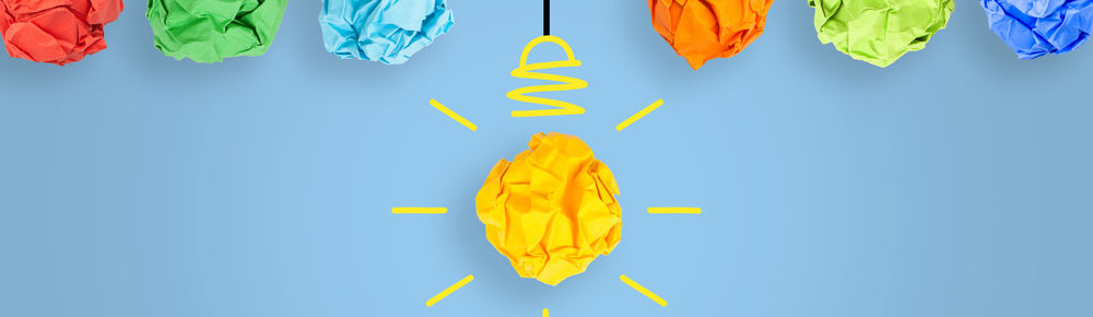 ©iStock\phototechno Auf dem Bild sind zerknüllte bunte Papierkugeln zu sehen, die wie Glühbirnen von der Decke hängen.